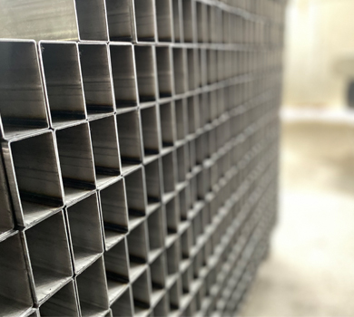 Steel pipes used as raw materials for standing desk frames, highlighting DELTA CAINA's commitment to quality materials in furniture hardware manufacturing.